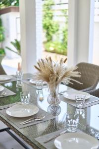 a table with plates and glasses and a vase with grass at Luxury Pool Villa in the Heart of the Chiang Mai in Chiang Mai