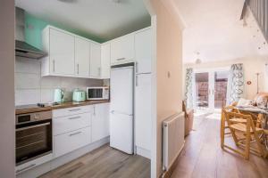 a kitchen with white cabinets and a table in it at Sea Cloud - 2-bedroom House with Courtyard Garden in Poole