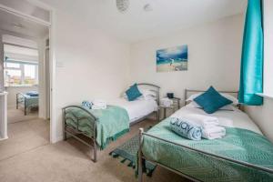a bedroom with two beds with blue pillows at Sea Cloud - 2-bedroom House with Courtyard Garden in Poole