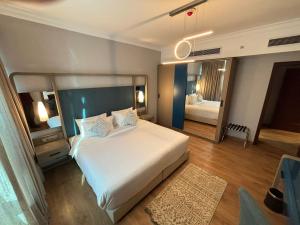 a bedroom with a large white bed and a mirror at Nile Suites Plaza Hotel Apartments in Cairo