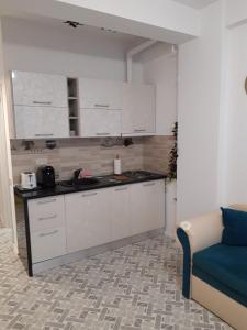 a kitchen with white cabinets and a blue couch at Seatime Studio in primul rând la mare in Mamaia Sat/Năvodari