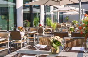 Un restaurante al aire libre con mesas, sillas y sombrillas. en Stadthotel am Römerturm, en Colonia