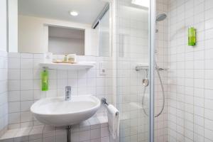 Un baño blanco con lavabo y ducha. en Stadthotel am Römerturm, en Colonia