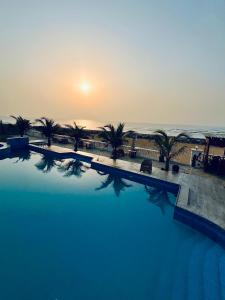 una grande piscina con palme e il tramonto di Coconut Pointe Villa & Beach Resort a Prampram