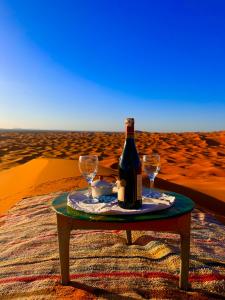a bottle of wine and two glasses on a table in the desert at Sultana Merzouga camp in Merzouga +72 photos
