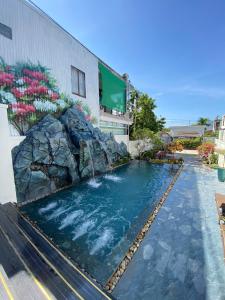 a swimming pool with a waterfall in front of a building at Eco Bliss Hotel in Thôn Lại Thê