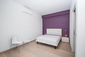 a bedroom with a white bed and a purple wall at Villa Ginevra- Private Pool in Orosei +35 photos