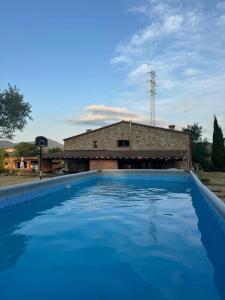 a large blue swimming pool in front of a building at Ca l'Esclatat in Santa María de Palautordera