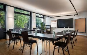 Una sala de conferencias con una mesa y sillas y una pantalla. en Stadthotel am Römerturm, en Colonia
