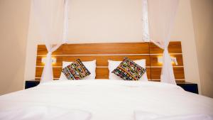 Un dormitorio con una cama blanca con dos almohadas. en Migano Residence, en Buyumbura