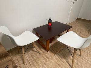 a table with two white chairs and a candle on it at Las Palmas Guesthouse in Shkodër