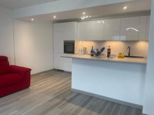 a kitchen with white cabinets and a red couch at Aurora Lake Apartment in Sala Comacina