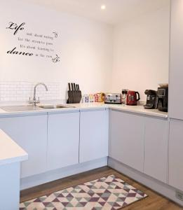 a kitchen with white cabinets and a sink at 2Bed 2Bath Private Balcony, Relaxing Waterfront View Apt, Parking FREE WiFi 10mins Media City, Salford Quays, Old Trafford, City Centre in Manchester