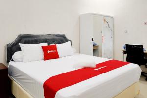 a bed with red and white pillows on it at RedDoorz near RSD Idaman Banjarbaru Syariah in Banjarbaru +10 photos
