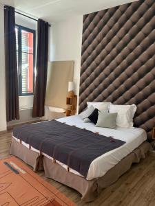 a large bed with a large padded headboard in a bedroom at La Maison de la Tour in La Tour