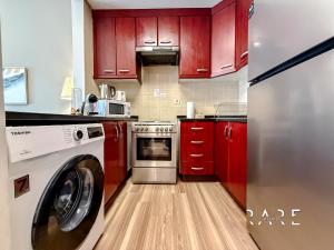 a kitchen with red cabinets and a washer at Rare Holiday Homes - Mediterranean Cluster - Near Ibn Battuta Mall - Discovery Garden - Building# Med 49 - R514 in Dubai