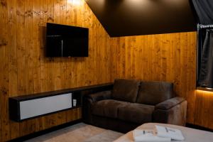 a room with a couch and a tv on a wooden wall at Bio Resort Čičkova in Arilje