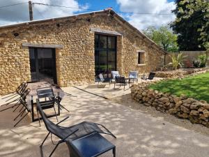 a stone house with chairs and a grill in front of it at L'Escale Nobilienne in Nouaillé-Maupertuis