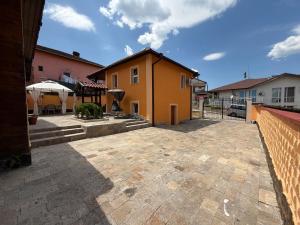 a large patio in front of a yellow house at Къща за гости Леон in Belogradchik