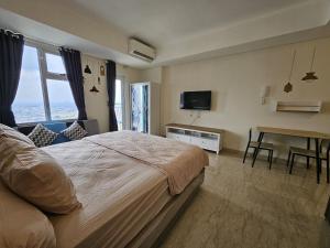 a bedroom with a bed and a desk and a television at Apartment Studio Penthouse Podomoro in Medan