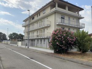 a white building with balconies and a bush with pink flowers at Salix Aurea in San Martino Siccomario