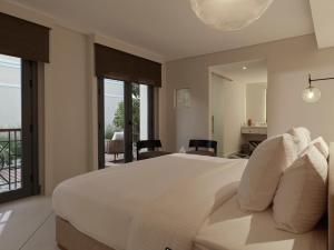 a bedroom with a large white bed and a balcony at The Chedi El Gouna in Hurghada