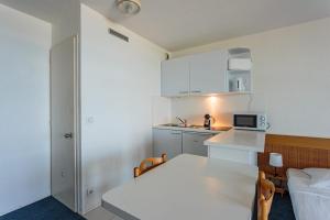 eine kleine weiße Küche mit einem Bett und einem Tisch in der Unterkunft Studio Helder vue mer - Welkeys in Biarritz