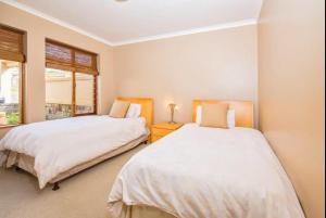 克尼斯纳Pezula Golf Villa的卧室设有两张床,带两个窗户 更多3张照片