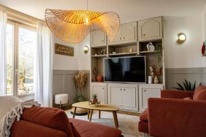 a living room with a couch and a tv at Gite Au Charme des Iris in Plérin