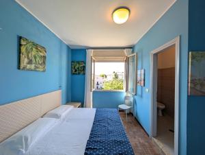 a blue bedroom with a bed in a room with a window at Alloggi San Marco in Caorle