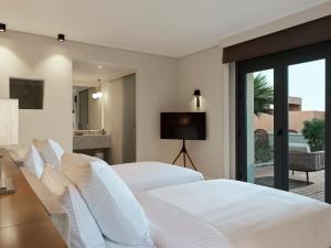 a bedroom with a white bed and a television at The Chedi El Gouna in Hurghada