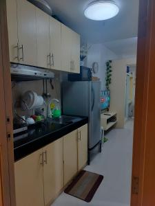 a kitchen with white cabinets and a stainless steel refrigerator at Cozy Condo in Quezon City with Private Pool in Manila