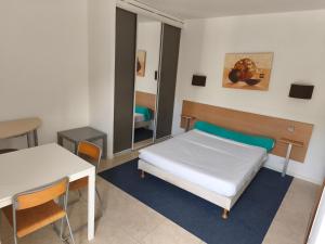 a bedroom with a bed and a table and a mirror at Residella hôtel in Gémenos