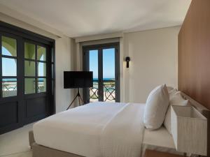 a bedroom with a large white bed and a balcony at The Chedi El Gouna in Hurghada