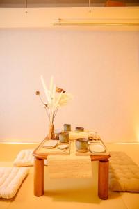 a coffee table with plates and flowers on it at 和605 名駅徒歩圏 地下鉄徒歩3分 最大4名 洗面台 浴室 トイレ別 長期滞在可乾燥機付き in Nagoya