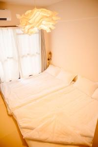 a white bed in a bedroom with a window at 和605 名駅徒歩圏 地下鉄徒歩3分 最大4名 洗面台 浴室 トイレ別 長期滞在可乾燥機付き in Nagoya +26 photos