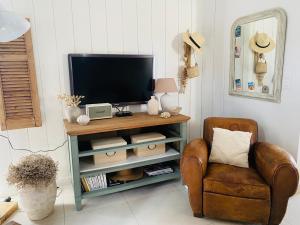 a living room with a television and a chair at Maison proche plage et Golf in Moliets-et-Maa