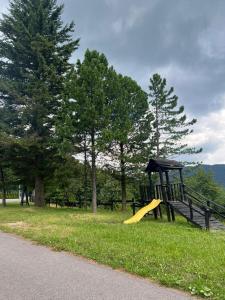 a playground with a yellow slide in the grass at Apartmán Kľak in Fačkov