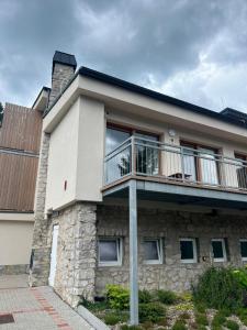 a stone house with a balcony on top of it at Apartmán Kľak in Fačkov +27 photos
