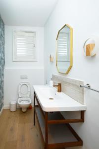 a bathroom with a sink and a toilet and a mirror at 2-Bedroom Getaway- Comfort and Style in Trofwi