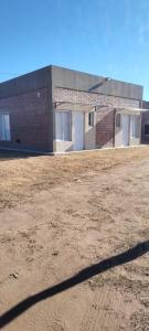 a brick building with white doors in a field at OMA Departamentos por día -1 in General Acha