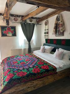 1 dormitorio con 1 cama con colcha colorida en Pensiunea Casa Cezara, en Silvaşu de Jos