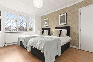 two beds in a room with two windows at Six Bedroom House by Brookland Stays Serviced Accommodation Short Lets Hertfordshire with Free WiFi in Leavesden Green