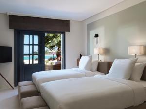 a hotel room with two beds and a television at The Chedi El Gouna in Hurghada