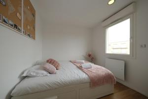 een slaapkamer met een bed met roze kussens en een raam bij Rouen - Bienvenue chez Aurélie in Rouen