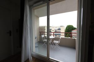 een glazen schuifdeur met een tafel en stoelen op een balkon bij Rouen - Bienvenue chez Aurélie in Rouen