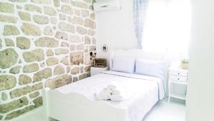 a white bed in a room with a stone wall at Morlimon in Alaçatı