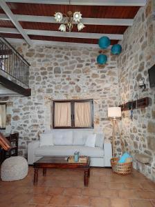 a living room with a white couch in a stone wall at Epavli Veneti in Parga