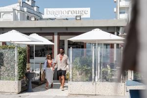 a man and woman walking down a sidewalk in front of a store at Rouge International Resort in Milano Marittima +173 photos
