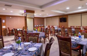 a dining room with tables and chairs and a television at Hotel Gopalapuram International in Pollāchi